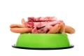 ein Fressnapf gefüllt mit Fleisch und Wurst vor weißem Hintergrund