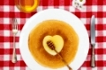 Pancakes heart with honeyflower and cutlery, top view