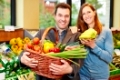 Glückliches Paar im Bioladen kauft frisches Obst und Gemüse