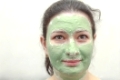 Young woman applying green algae facial mask.