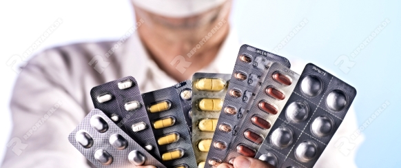 Arzt hält eine Menge Blister mit verschiedenen Medikamenten in den Händen.