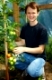 Junger Landwirt hockt neben Tomaten im Gewächshaus