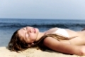 sexy Frau im Bikini liegt im Sand am Strand und entspannt