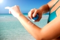 Woman applying sunscreen on her arm on a beach