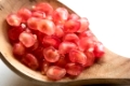 Pomegranate fresh pink seeds close-up in a wooden spoon