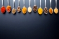 Various spices in spoons on black background. Top view.