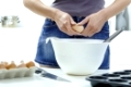 Female hands breaking eggs into a bowl. 