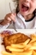 Happy little italian girl eating breaded meat and French fries with a fork,  in a restaurant. The child is wearing flower jacket. Ideal for concepts.