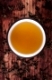 Traditional tea ceremony. Tea in cup with dry tea crop on brown wooden background, top view. 
