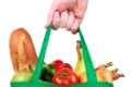 Eine Hand hält eine grüne Einkaufstüte, die mit Lebensmitteln gefüllt ist