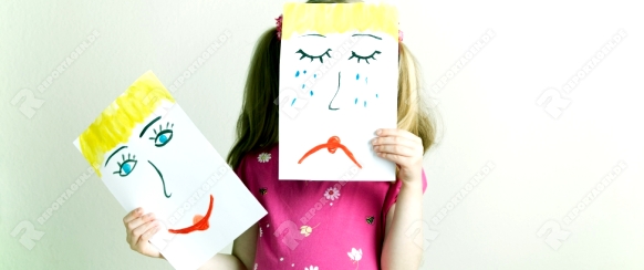 Blondes Mädchen mit Masken mit gemaltem traurigen und glücklichem Gesichtsausdruck