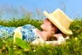 Young teenage girl resting on summer meadow in straw hat