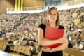 Studentin mit Aktenordner in einem Hörsaal.