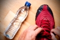 Jogger at home, tying his sneakers with a water bottle nearby