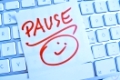 Ein Notizzettel liegt auf der Tastatur eines Computers zur Erinnerung: Pause