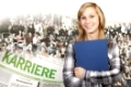 Beautiful blonde girl in front of a large group of young people with a newspaper on which the german word 