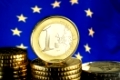 Eine ein Euro Münze vor einer Europäischen Flagge