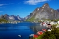 Scenic town of Reine, Norway on sunny summer day with picturesque fjord and surrounding mountain peaks