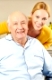 Frau und alter Mann im Rollstuhl lächeln gemeinsam
